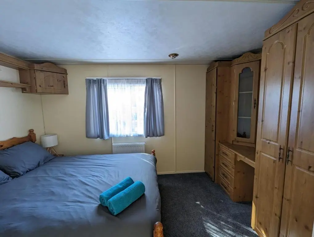 a bedroom with a blue bed and a window at Highland getaway in kingussie golf club in Kingussie