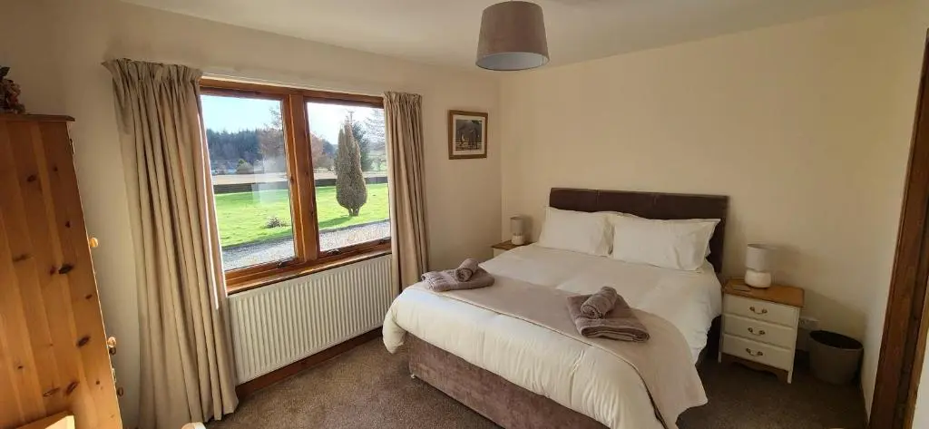 a bedroom with a bed and a large window at Dail Daraich in Munlochy