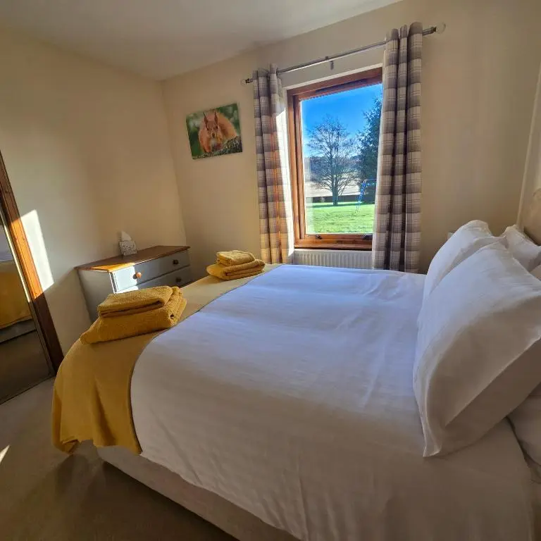 a bedroom with a large white bed with a window at Dail Daraich in Munlochy