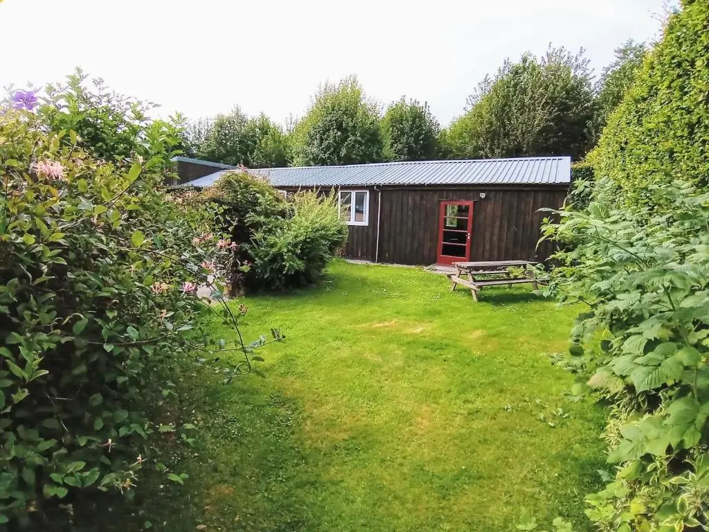 a garden view of a cabin with a red door at Strathpeffer Holiday Cottages in Strathpeffer