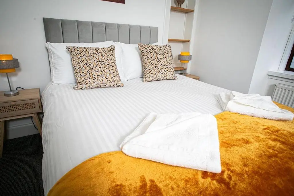a white bed with two towels on top of it at Castle Grant - 4 Bed Cottage in Gardenstown in Gardenstown
