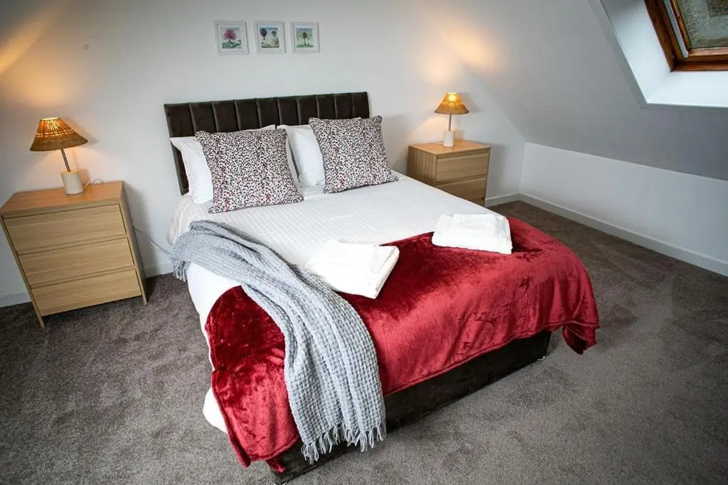a bedroom with a large bed with a red blanket at Castle Grant - 4 Bed Cottage in Gardenstown in Gardenstown