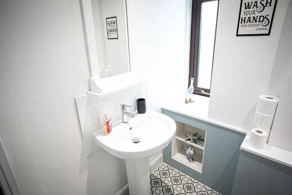 a white bathroom with a sink and a mirror at Castle Grant - 4 Bed Cottage in Gardenstown in Gardenstown
