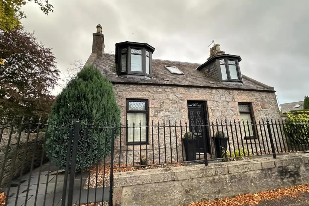 an old stone house with a black fence at 3 Bed Cottage Sleeps 2 with Parking Garden & Wifi in Aberdeen