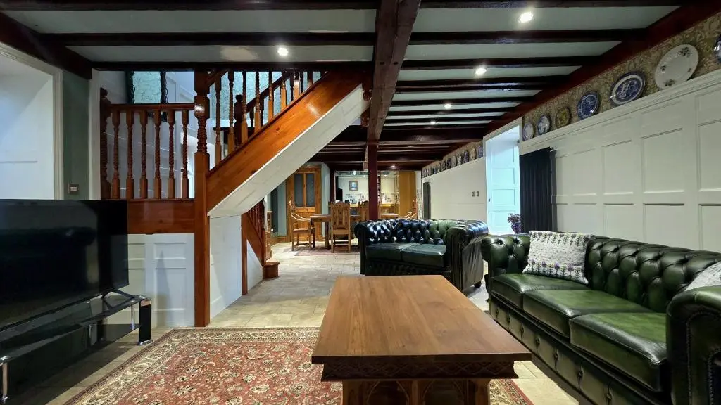 a living room with couches and a table and a tv at The Old Stables in Fort Augustus