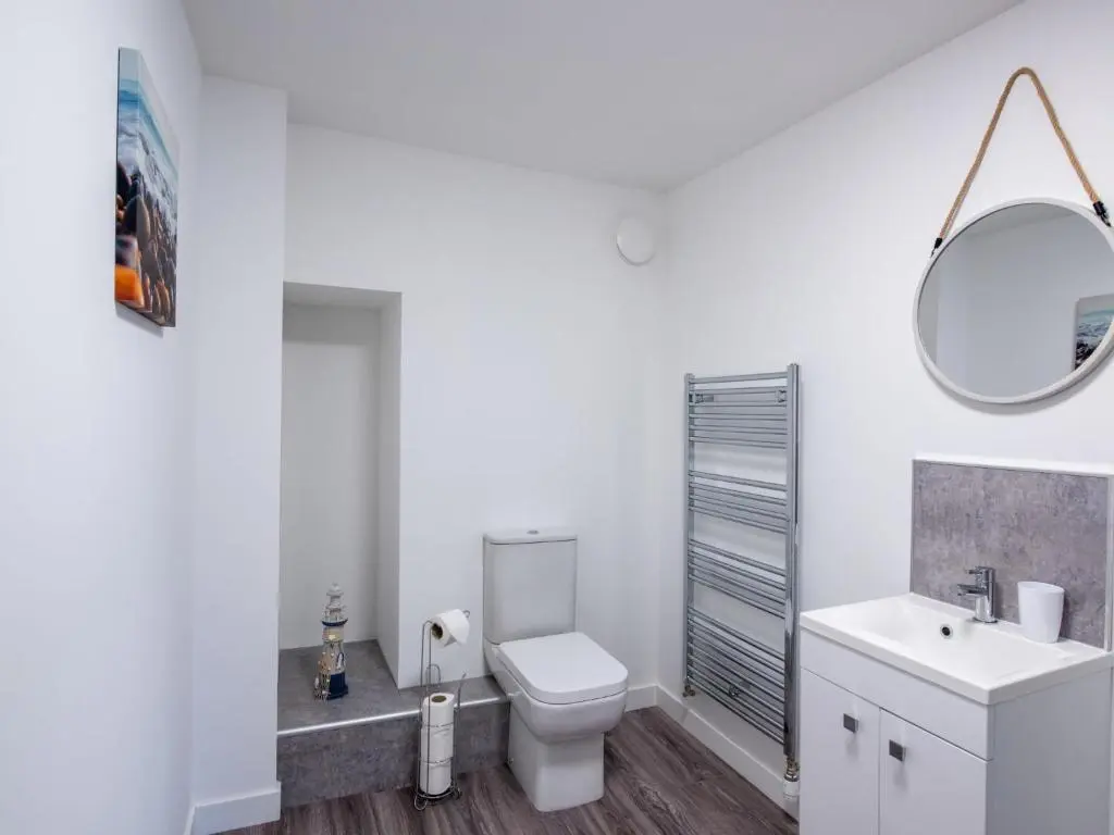 a white bathroom with a toilet and a mirror at Apartment Harbour Nights Deluxe 7E by Interhome in Lossiemouth
