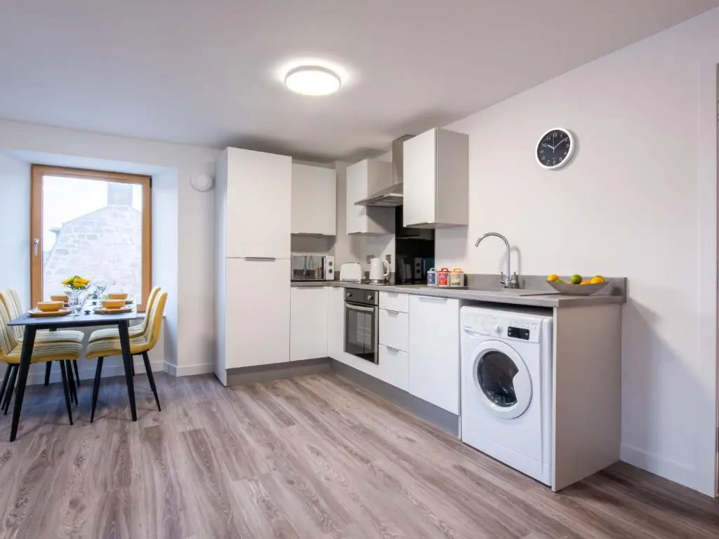 a kitchen with a washing machine and a table at Apartment Harbour Nights Deluxe 7F by Interhome in Lossiemouth