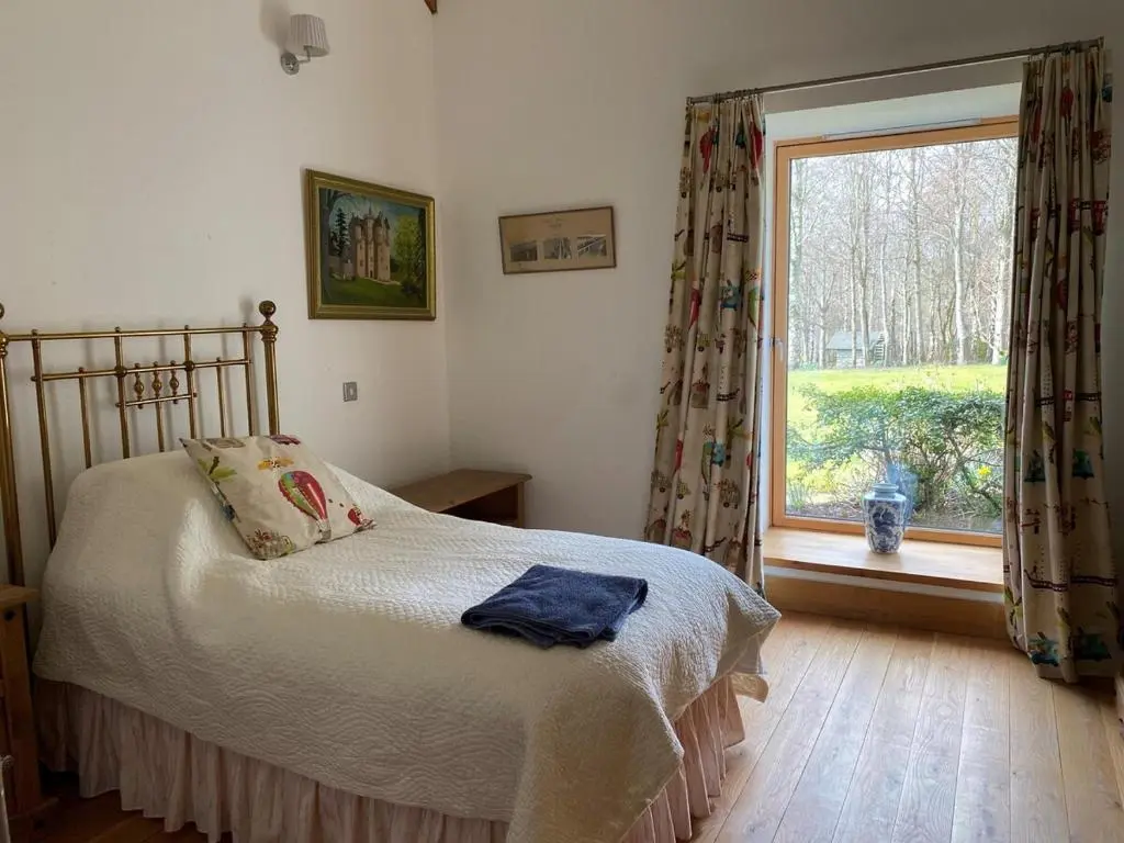 a bedroom with a bed and a large window at Spacious, cosy 6 bedroom house which sleeps 11 in Banchory