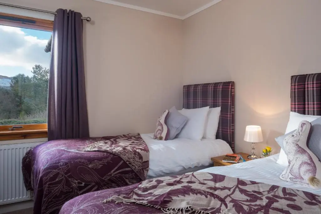 two beds in a room with a window at Cairn Eilrig - Seasgair Lodges in Loch Morlich