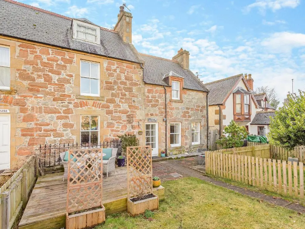 an exterior view of a brick house with a wooden deck at Ord Cottage in Kildary