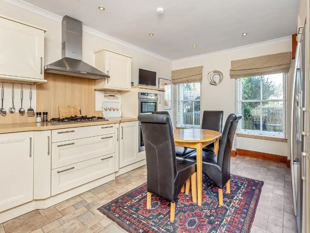 a kitchen with a wooden table and black chairs at Ord Cottage in Kildary