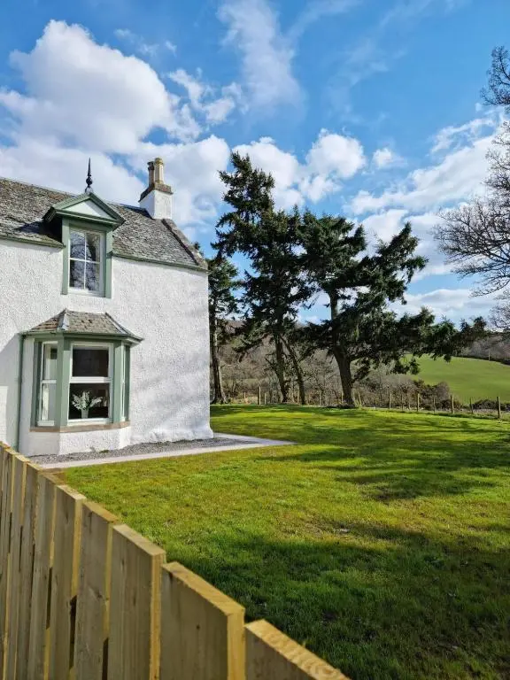 a white house with a fence and a green yard at 3 Bed House near Loch Ness in Inverness