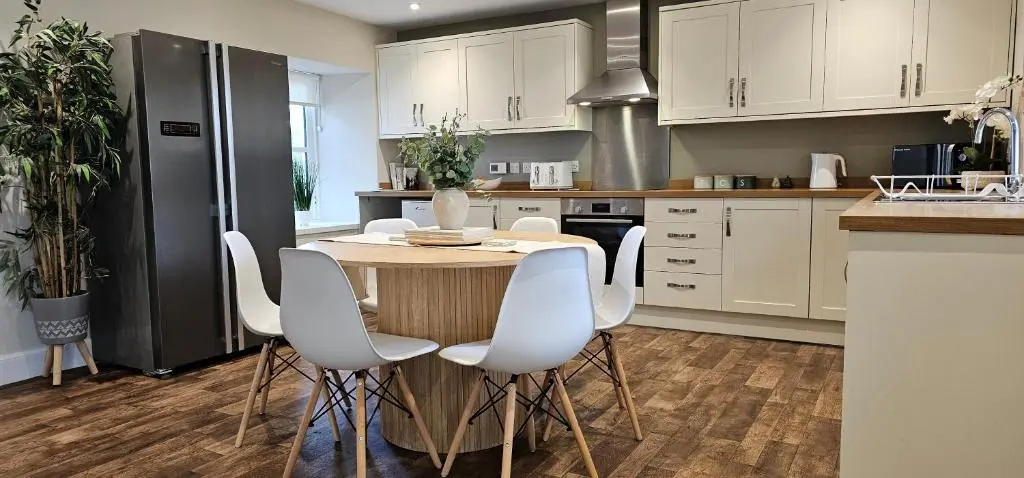 a kitchen with a wooden table and white chairs at 3 Bed House near Loch Ness in Inverness