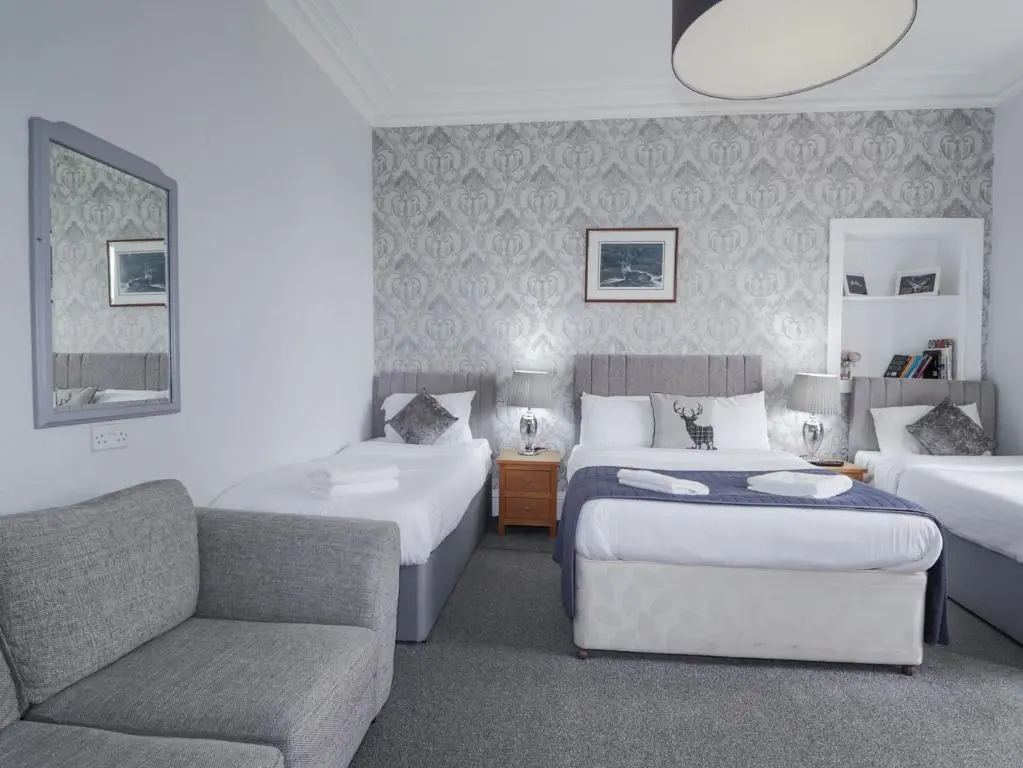 a hotel room with two beds and a couch at Glenspey in Kingussie