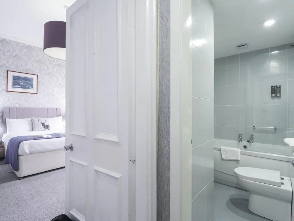 a bathroom with a sink and a toilet and a bed at Glenspey in Kingussie