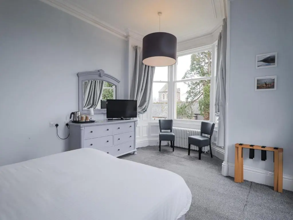 a bedroom with a bed and a tv and a window at Glenspey in Kingussie