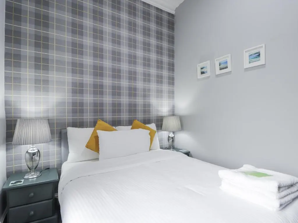 a bedroom with a white bed and a blue tiled wall at Glenspey in Kingussie