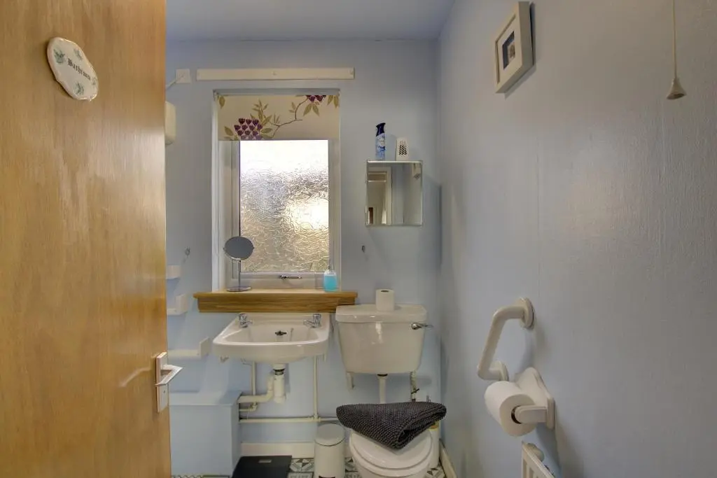a bathroom with a sink and a toilet and a mirror at Kavija, Invergordon in Invergordon