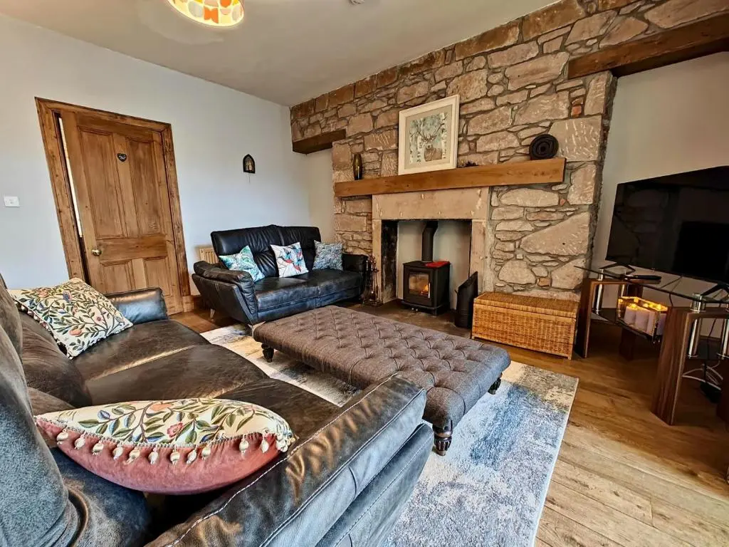 a living room with a couch and a stone fireplace at 3 Bed in Aviemore oc-s30815 in Aviemore
