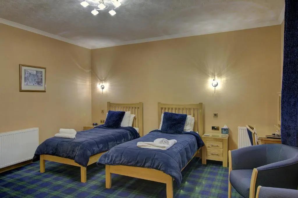 two beds in a room with a chair and a desk at The Clachan, Wick in Wick