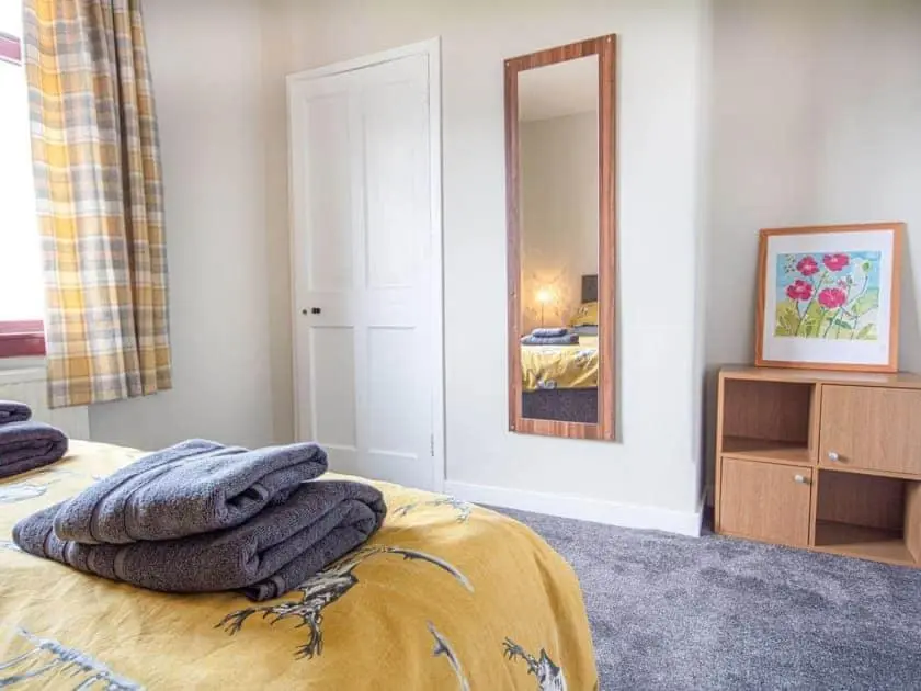 a bedroom with a bed with a mirror and a dresser at Auld House in Brora