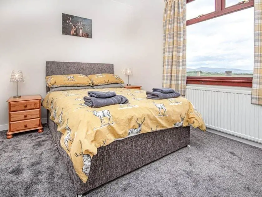 a bedroom with a large bed with a window at Auld House in Brora