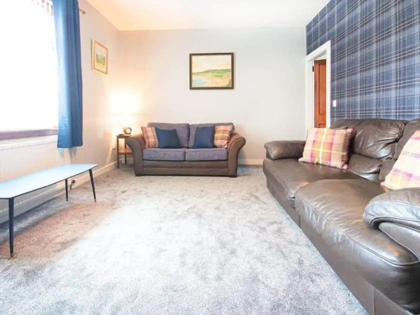 a living room with a couch and a table at Auld House in Brora