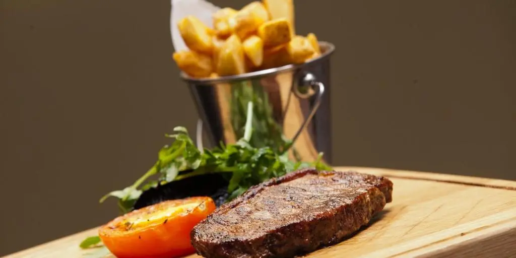 a steak and french fries on a table with a container of food at Crowne Plaza Aberdeen Airport by IHG in Dyce