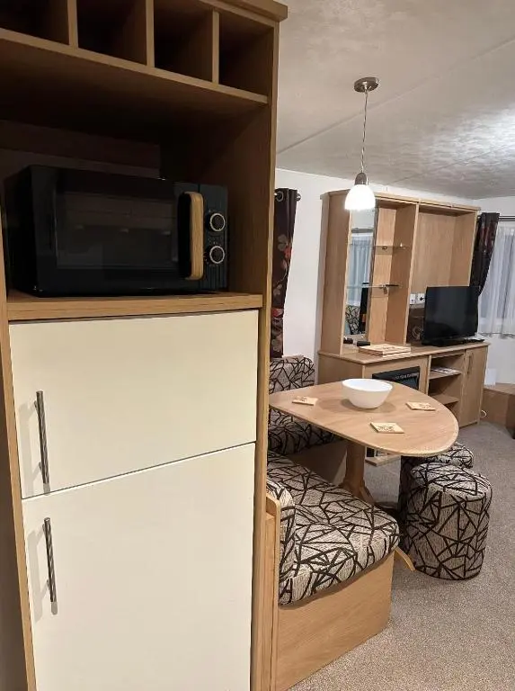 a living room with a table and a microwave at Covesea View Silver Sands in Lossiemouth