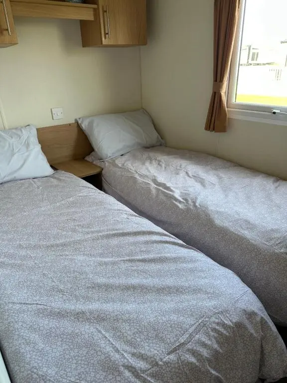 two beds in a small room with a window at Covesea View Silver Sands in Lossiemouth