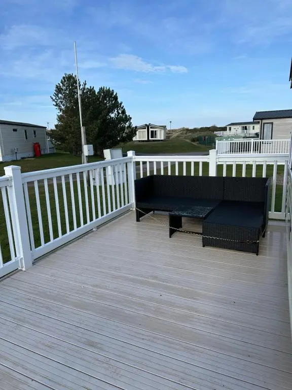 a bench on a deck with a white fence at Covesea View Silver Sands in Lossiemouth