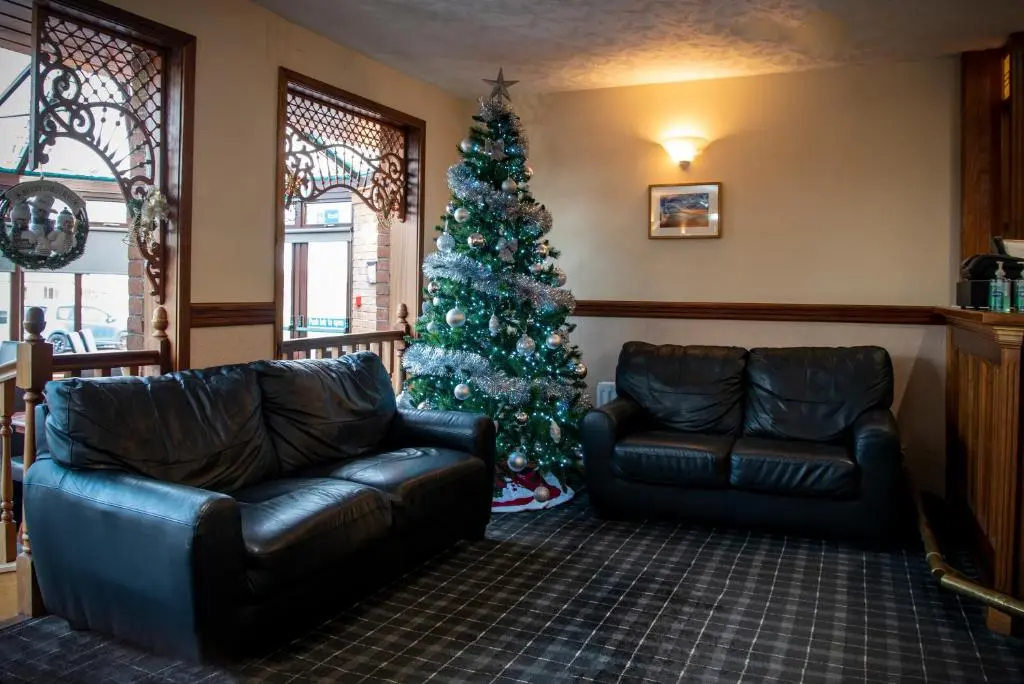 a living room with a christmas tree and two leather couches at Findlay's in Fraserburgh