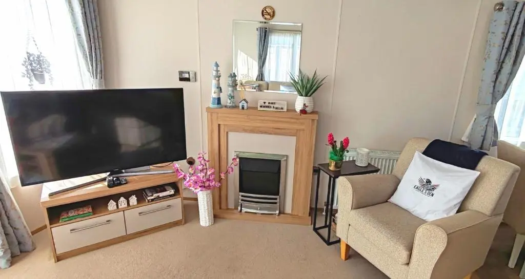 a living room with a flat screen tv and a fireplace at Eagle's Den Caravan Holiday Retreat in Lossiemouth
