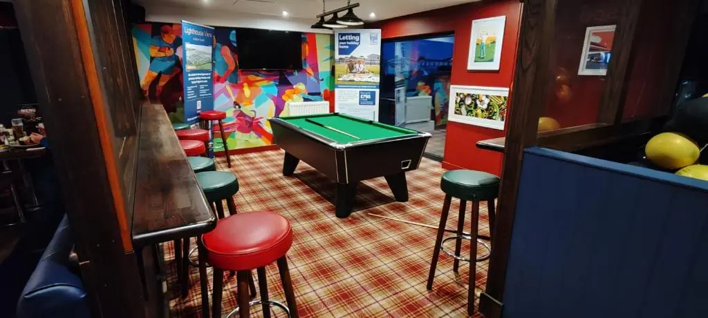 a bar with a pool table and some stools at Eagle's Den Caravan Holiday Retreat in Lossiemouth