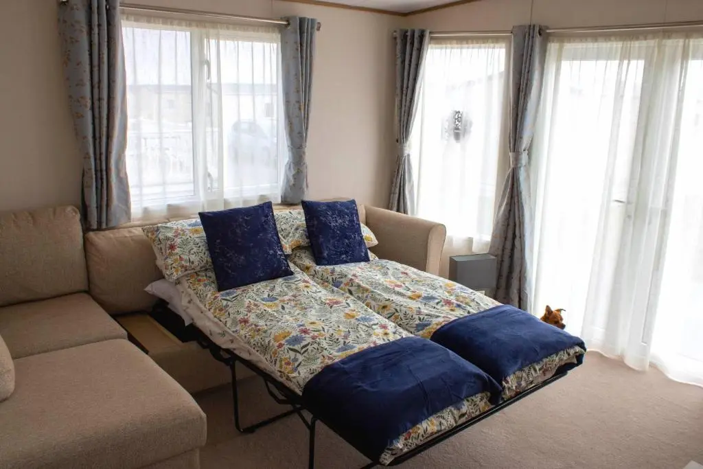 a bedroom with a bed and a couch and windows at Eagle's Den Caravan Holiday Retreat in Lossiemouth