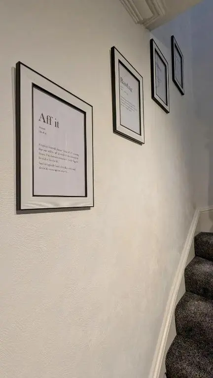 a wall with three pictures on a wall with stairs at The Wee Heilan' Dram in Keith
