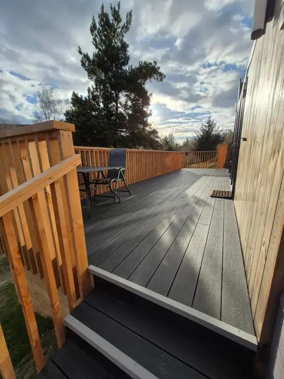 a wooden deck with a bench on a house at Little Getaway in the Highlands, private sauna and stargazing geodome in Garve