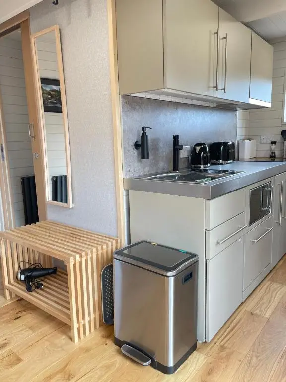 a kitchen with a stove and a trash can at Little Getaway in the Highlands, private sauna and stargazing geodome in Garve