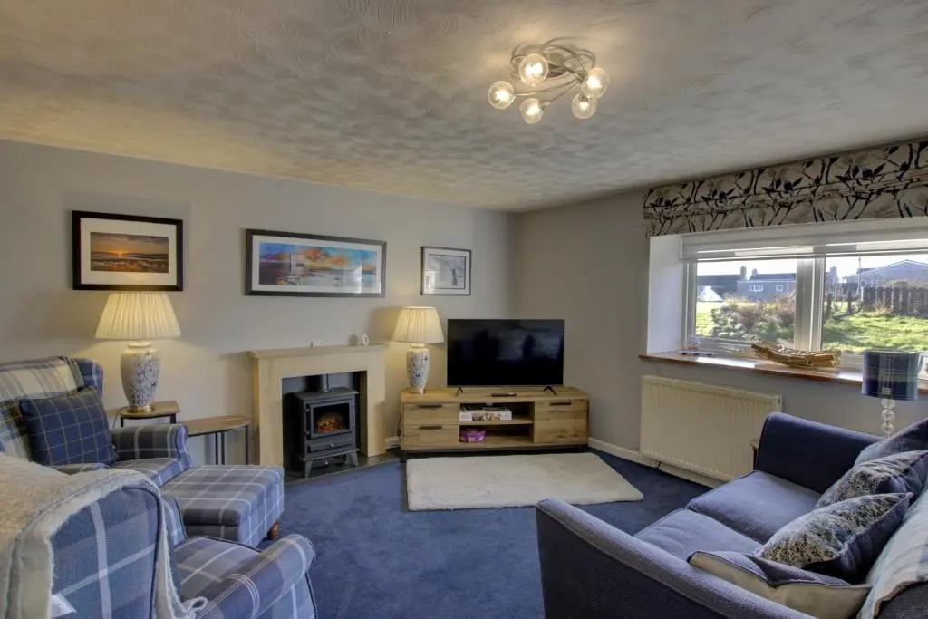 a living room with couches and a tv and a fireplace at Beach Croft, Brora in Brora