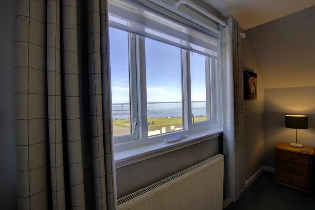 a window in a bathroom with a view of the ocean at Beach Croft, Brora in Brora