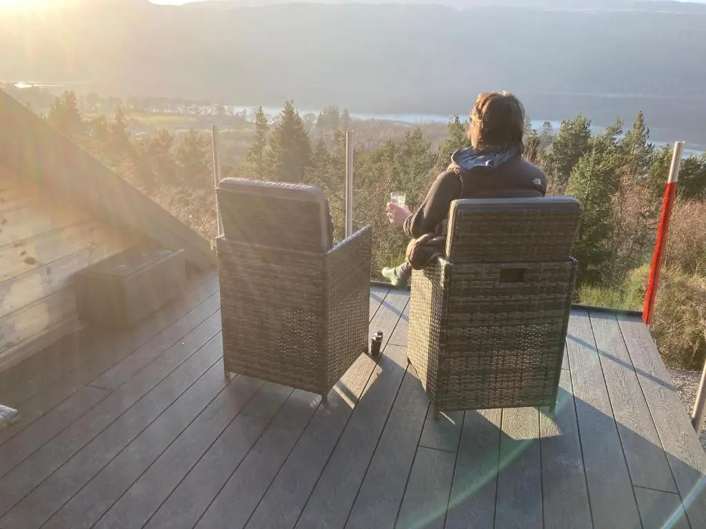 a woman sitting in a chair on a balcony at The Loft at Log Ness in Inverness