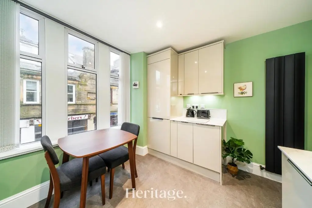 a kitchen with a table and chairs and some windows at The Copper Loft Apartment, Keith in Keith