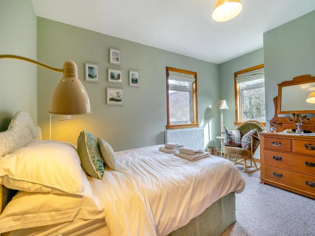 a bedroom with a bed with a lamp and a dresser at Clunie Dam Lodge in Blair Atholl