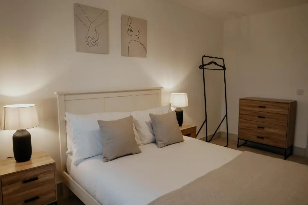 a bedroom with a white bed with two lamps and a dresser at Luxurious Apartment in Inverness in Inverness
