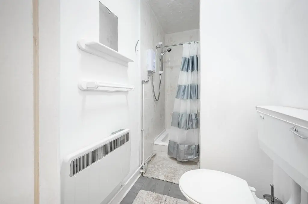a white bathroom with a toilet and a shower at 2 Bed Chalet - Sleeps 4 - River and mountain views in Strathpeffer