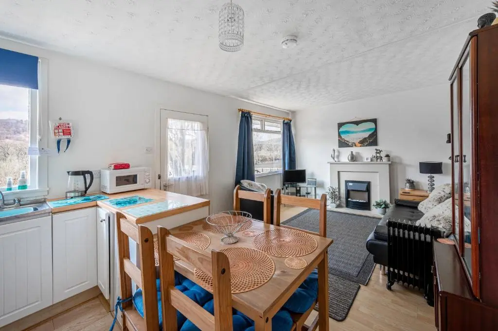 a kitchen and living room with a table and a kitchen and a dining room at 2 Bed Chalet - Sleeps 4 - River and mountain views in Strathpeffer