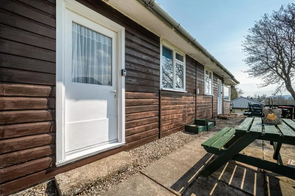 a wooden house with a picnic table and a door at 2 Bed Chalet - Sleeps 4 - River and mountain views in Strathpeffer