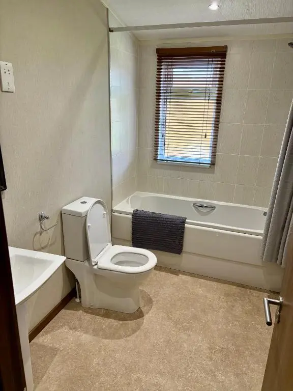 a bathroom with a toilet and a tub and a sink at Hepburns Lodge 19 in Strachan