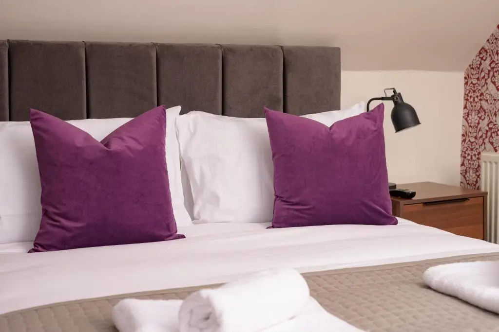 a bedroom with purple pillows and a white bed at Netherley Rooms in Ballater