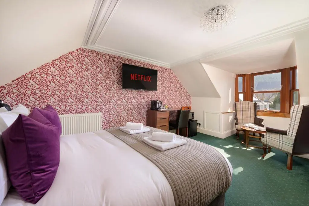 a bedroom with a large bed with purple pillows at Netherley Rooms in Ballater